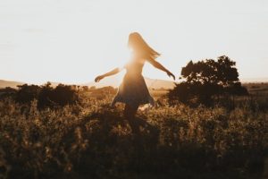 woman moving happily as the sun sets to give the idea that it is important to enjoy your qigong practice