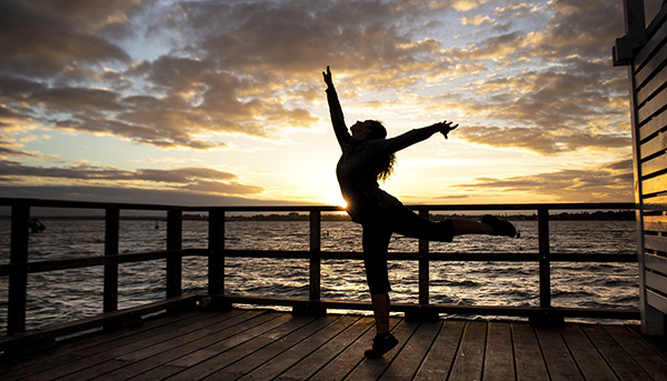 Girl dancing in the sunset to show how practicing qigong leads to a richer and more joyful experience of life